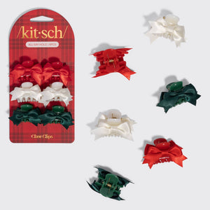 A 3-piece hair claw clip set by Kit-sch, featuring red, white, and green satin ribbon bows, shown both in its retail blister packaging and individually on a light gray background.