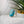 Turquoise ring with gold accents on a white stone surface with a plant in the background