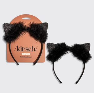 Black cat ear headband with fluffy faux fur and glittery ears, shown both on its peach-colored retail card and as a loose headband on a light gray background. The card shows the brand name 'kit-sch'.